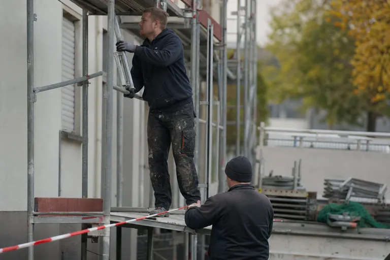 Gerüstbauer führt eine Änderung am abgesperrten Fassadengerüst aus